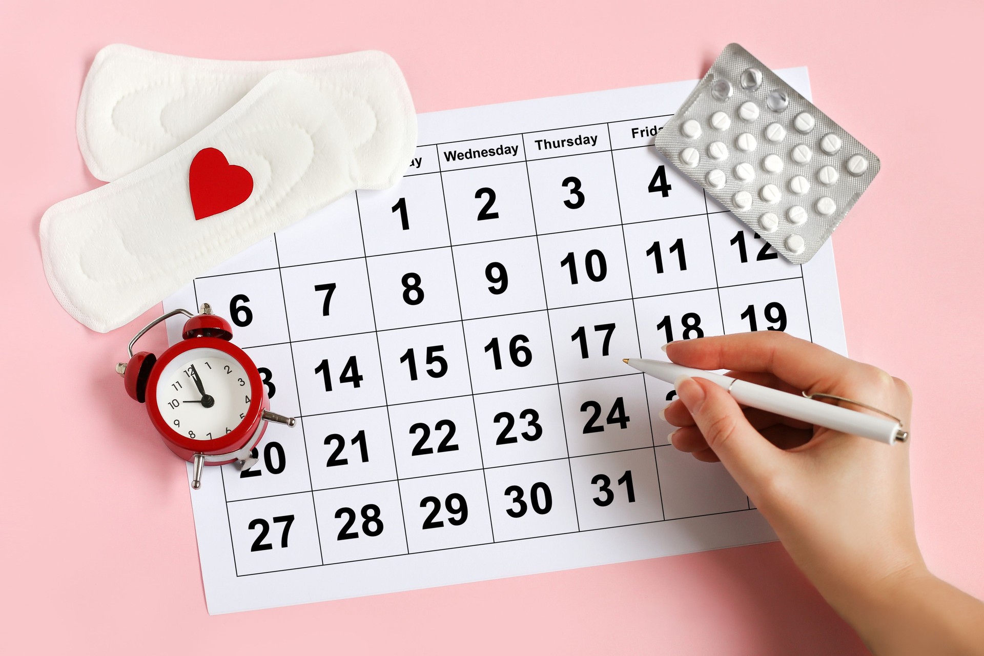 Calendario de menstruación con compresas, despertador, píldoras anticonceptivas hormonales. Concepto del ciclo menstrual femenino. Concepto de retraso menstrual