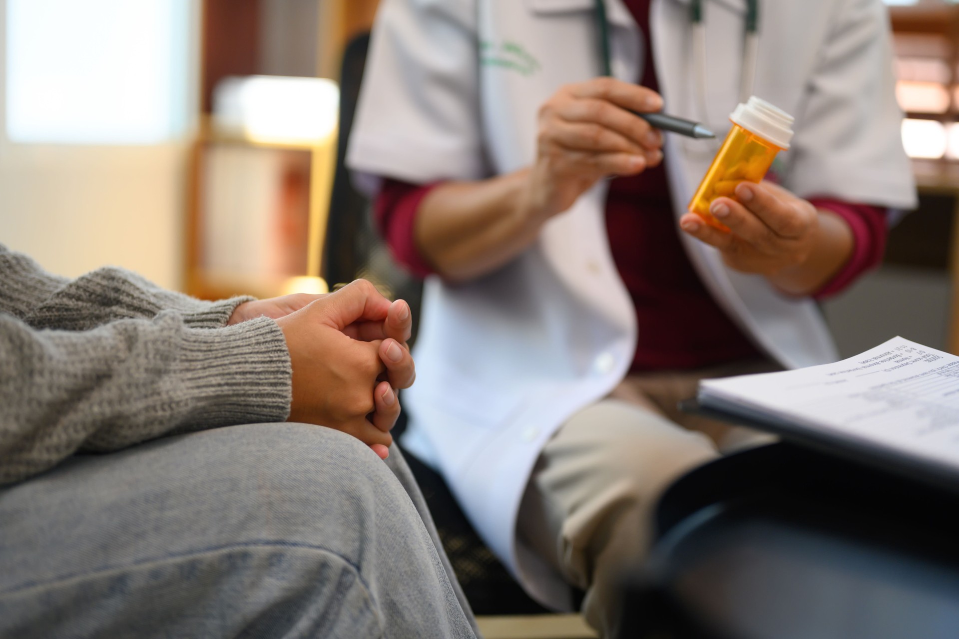 El médico sostiene un frasco de medicamento recetado y explica o discute el plan de tratamiento con el paciente.