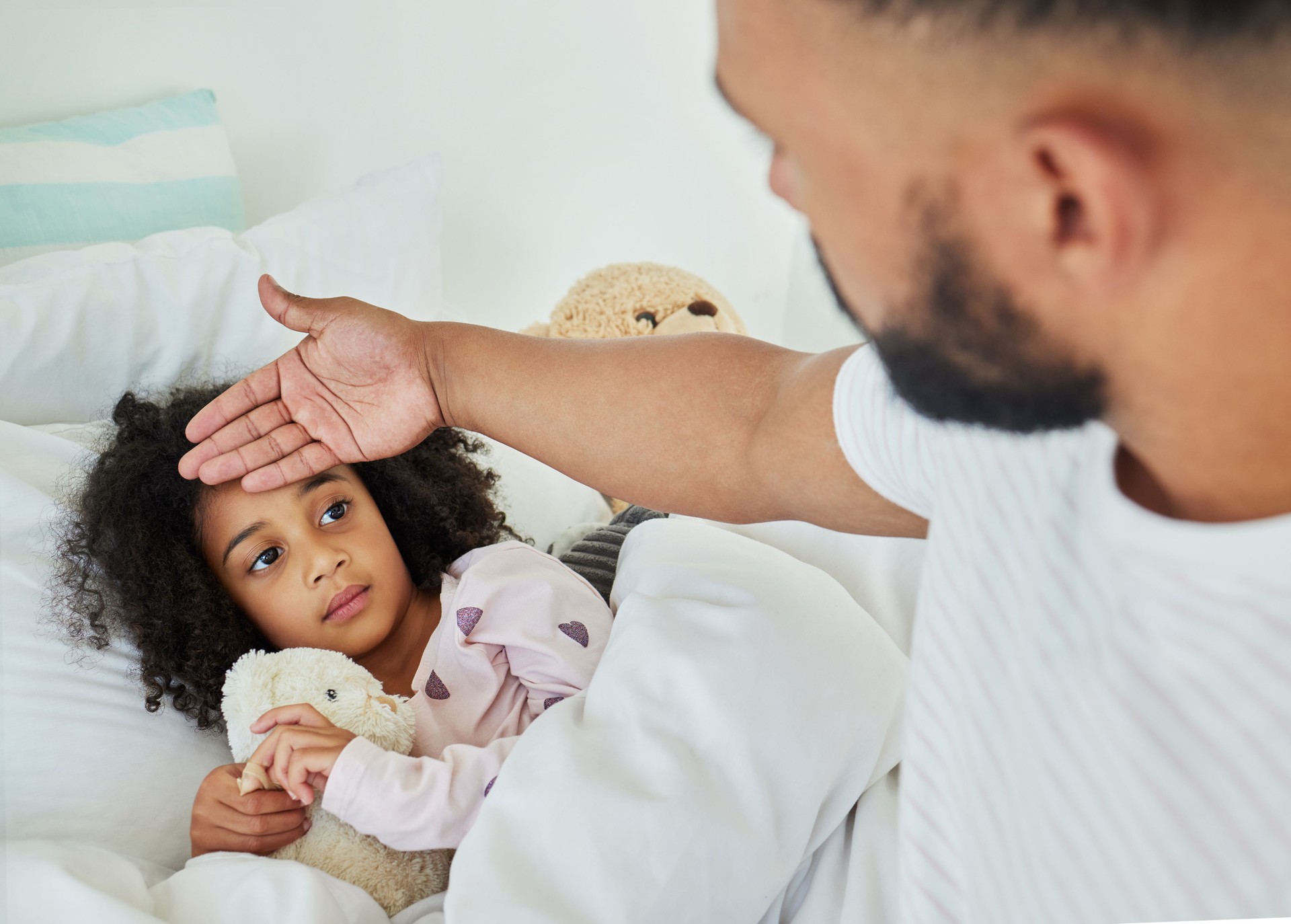 Foto de un joven padre cuidando a su hija enferma en casa